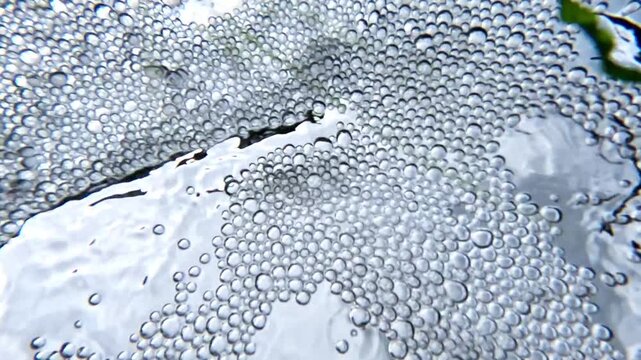 Bottom-up view, air bubbles in white foam on the surface of freshwater flowing from underground springs into the Black Sea