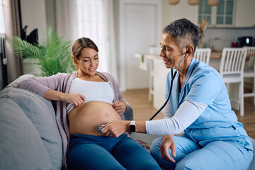Obraz premium Visiting nurse examining pregnant woman's belly with a stethoscope at home.
