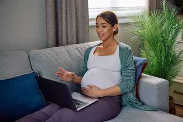 Obraz premium Happy expectant mother talking during video call over a laptop at home.