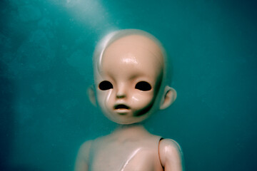 Creepy doll face in dark dirty blue water