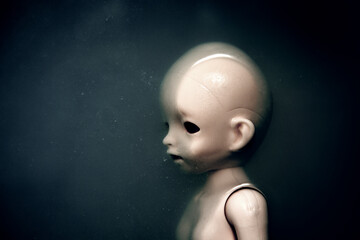 Creepy doll face in dark dirty water