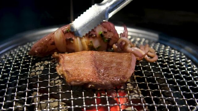 Top-down view of beautifully marbled raw Hanu beef slices, mushrooms, and garlic cooking on a circular charcoal grill, surrounded by an assortment of delicious Korean banchan side .