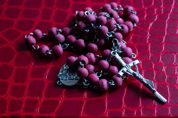 Rosary with rich red wooden beads and a detailed metal crucifix laying on red background
