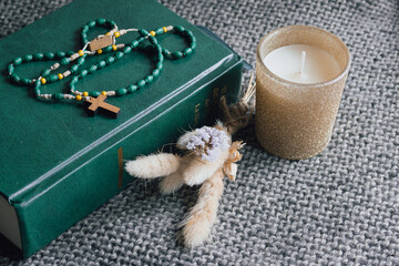 Christian rosary with wooden cross and green beads finding peace on top of a Holy Bible.