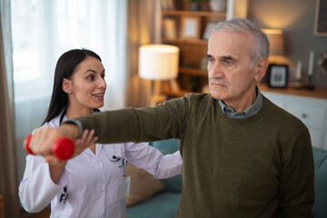 Fototapeta premium Nurse assisting senior man with physical therapy exercise