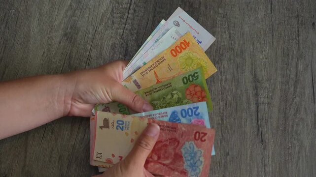 Human hand showing various argentine peso banknotes, representing inflation, economic crisis, finance, and currency exchange