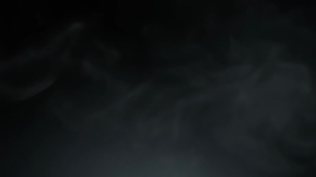 Wisps of white smoke dance and swirl against a dark, moody background. Ethereal smoke patterns create a mysterious and atmospheric visual effect.