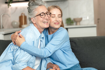 Fototapeta premium Elderly mother and adult daughter enjoy a joyful moment in their cozy home