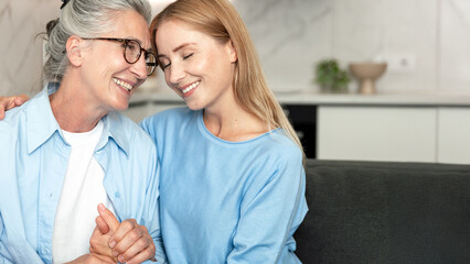 Elderly mother and adult daughter share a moment of joy in their living room