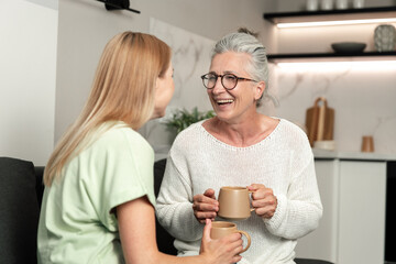 Elderly mother and adult daughter share a happy moment in their cozy apartment