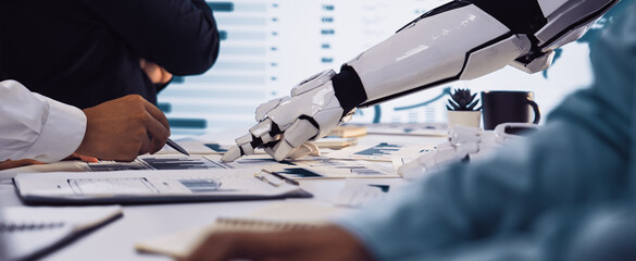 A futuristic scene showcasing a robot arm interacting with data charts in a sleek office environment. Professionals engage in discussion, emphasizing innovation and collaboration.Noogenesis