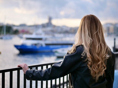 young woman looking out over harbor bay boats cityscape skyline back view travel
vacation leisure modern architecture building