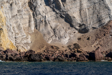 Rocky cliff wall with eroded textures and coastal stones by the sea