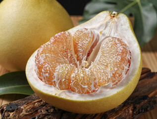 Cinematic close-up of a partially peeled pomelo exposing juicy pink-orange segments on a thick rind