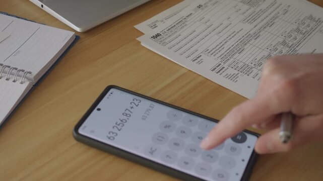 Man Filling In The Tax Form 1040 for 2025 Year. Person Calculates of Planning Budgets Yearly Personal Finance and Fills up US Tax Form 1040 For 2025 Year. Signing 1040 Income Tax Return For 2025 Year.