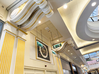 Naklejka premium Elegant indoor Trafford Centre atrium with gold decorative columns and curved ceiling lighting in Manchester UK mall
