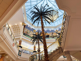 Naklejka premium Indoor Trafford Centre atrium in Manchester mall with glass ceiling palm trees and festive lighting
