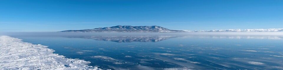 Obraz premium Majestic snow-covered mountain reflecting on frozen lake under clear blue sky