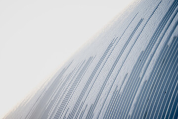 Abstract winter background of shallow ridges and lines in snow, close view of textured surface with smooth gradients and minimal composition in daylight