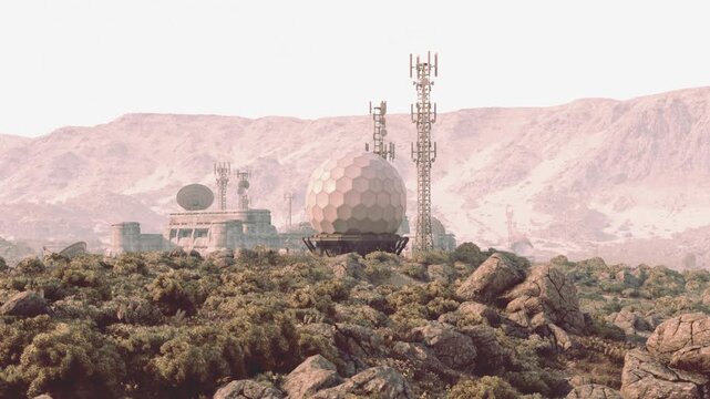 A military base is nestled among rugged mountain terrain, featuring communication towers and a large radar dome. The structure blends into the rocky landscape, highlighting its strategic location.