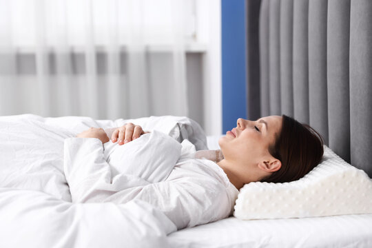 Young woman sleeping on bed with orthopedic pillow at home. Healthy posture