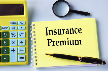INSURANCE PREMIUM - words in a notebook with a calculator, magnifying glass and pen in the background