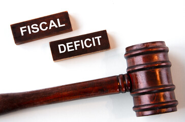 FISCAL DEFICIT - words on wooden brown bars on a white background with a judge's gavel