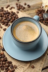 Aromatic coffee in cup and beans on wooden table, closeup