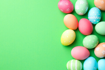 Beautiful decorated Easter eggs on green background, flat lay. Space for text
