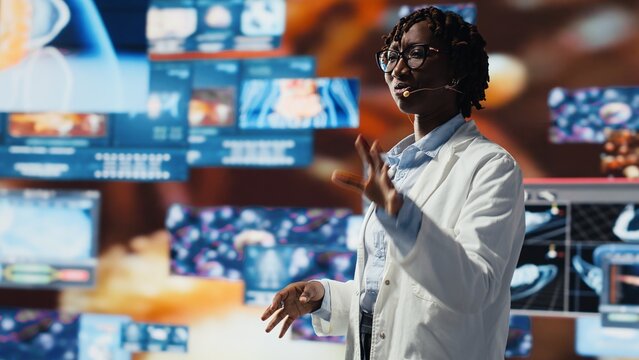 Smiling scientist doing key note presentation with xray scans on digital videowall. Jolly woman sharing latest neurology research innovations to audience, showcasing pictures of human organs, camera B