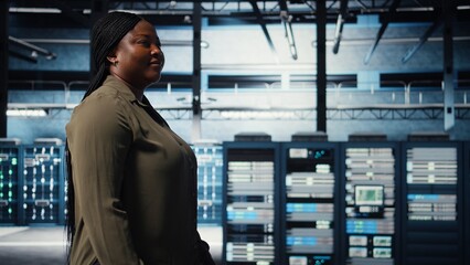 Technician in data center overseeing large scale IT gear to maintain seamless operations. IT professional walking in server hub, doing network management for increased uptime, camera A
