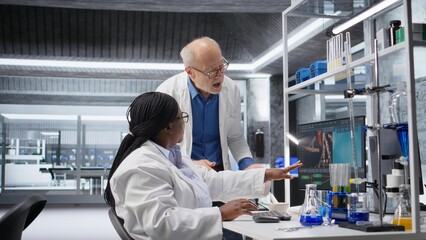 Woman scientist examines experiment data with coworker in a laboratory, driving progress in healthcare technology and clinical testing. Biotechnology research, pharmacology and digital health.