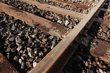 Railroad track detail texture. Rusty steel rail surface. Gravel ballast stones background. Industrial transport infrastructure pattern. Weathered railway metal closeup.