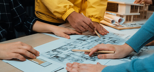 A vibrant scene depicting a collaborative design session where team members engage in planning an architectural project using blueprints and sketches, showcasing teamwork. SACTR