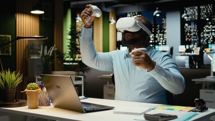 African american employee using AI tools with virtual reality late at night, working hard in the office with VR glasses to ensure fact checking and forecasting projections. Strategy room.