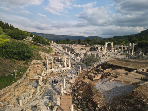 Aerial view reveals the Roman avenue and dense ruins in Ephesus Turkey Tourists move between columns and walls The colonnade lines the slope and the valley opens in the distance Historic stones line