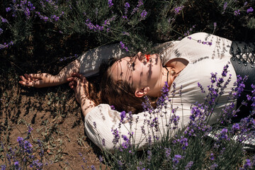 Woman lays in lavender field under sunlight during a clear day