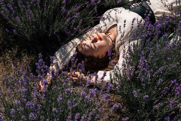 Woman lays in lavender field under sunlight during a clear day