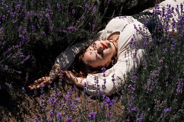 Woman lays in lavender field under sunlight during a clear day