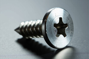 Extreme close up macro view of a silver metal screw head with star drive pattern isolated on a grey background representing construction and industrial hardware