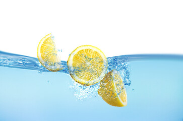 Fresh lemons falling into water against white background