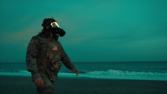 A patrol walk by an American soldier wearing a gas mask new the ocean at night