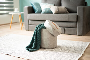 a room with a couch and a basket under a blanket on a white rug