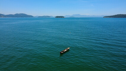 Obraz premium Aerial view of small boat floating alone on calm tropical sea