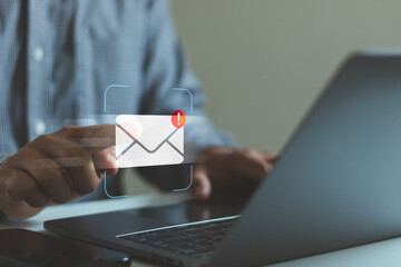 Businessman touching digital email notification icon on virtual screen with laptop, concept of online communication, inbox alert, business email marketing, customer support, data security technology.