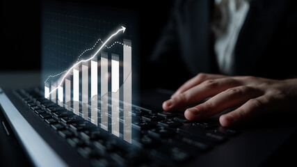 A businessman engages with a laptop as a virtual financial graph displays increasing data analytics, reflecting modern technology impact on business success. Impute