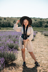 Woman sits in lavender field wearing a black hat and enjoying the sunlight during a warm day in summer