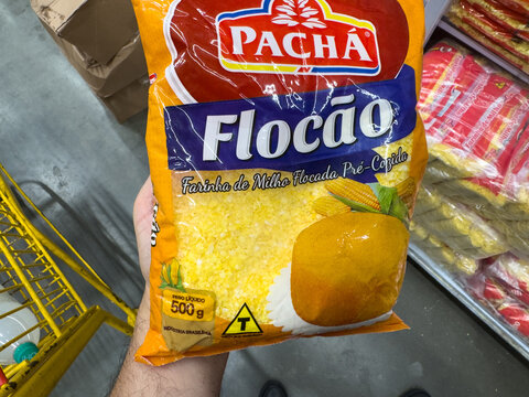 BELO HORIZONTE, MG/BRAZIL, JANUARY, 06, 2026: A hand holding a bag of Pacha Flocao cornmeal in a store aisle