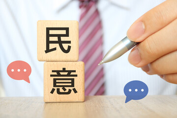 民意を示す木製ブロックと政治家の対話イメージ。