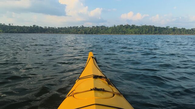 Yellow kayak on the Xingu River with Amazon rainforest in background